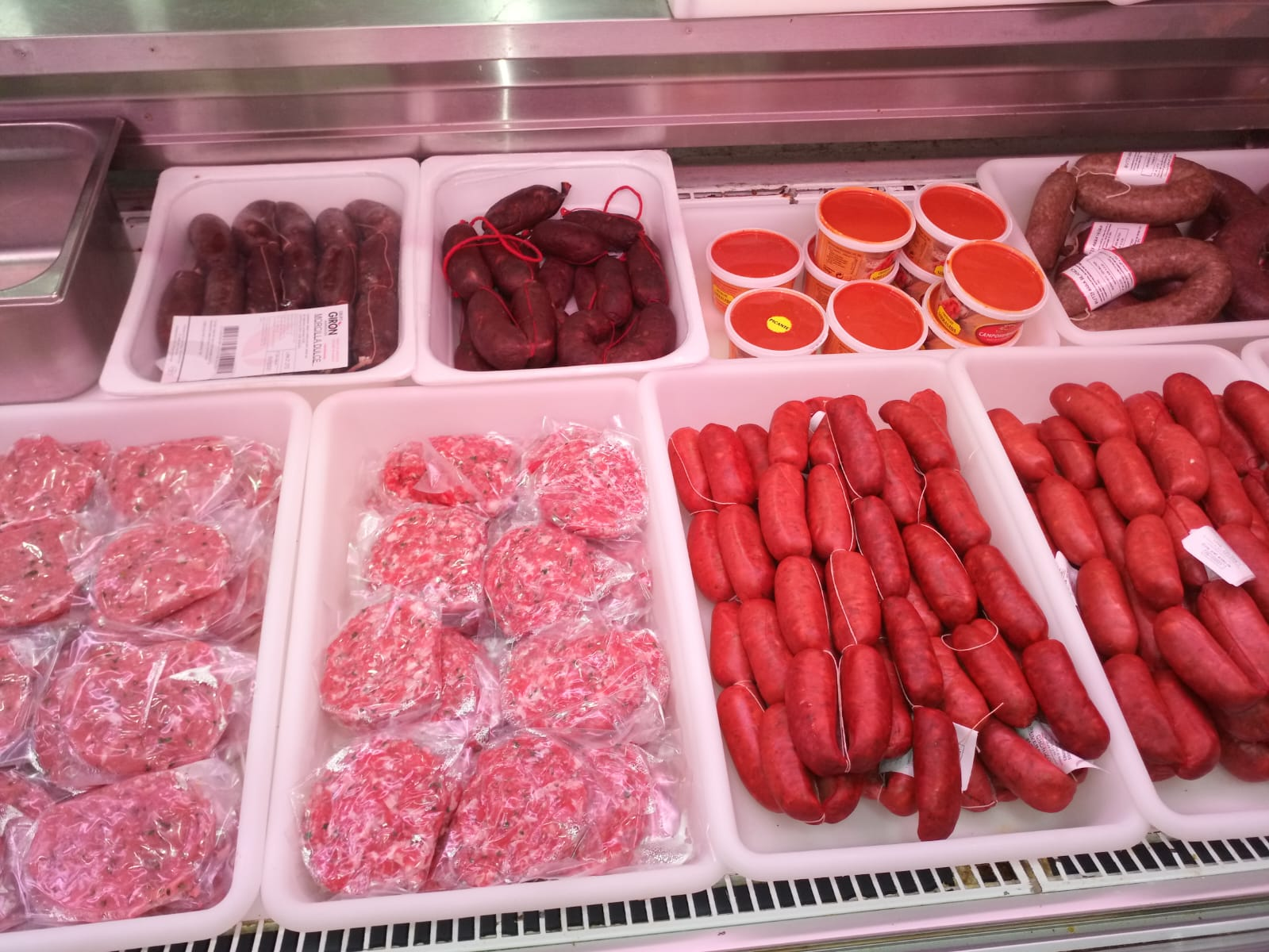 Mostrador refrigerado con selección de carnes frescas: hamburguesas, salchichas, morcilla y carne picada envasada