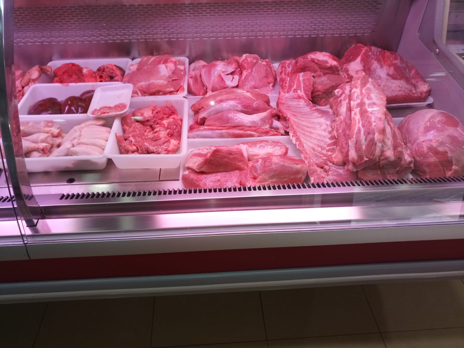 Surtido de carnes y embutidos frescos en mostrador refrigerado de carnicería